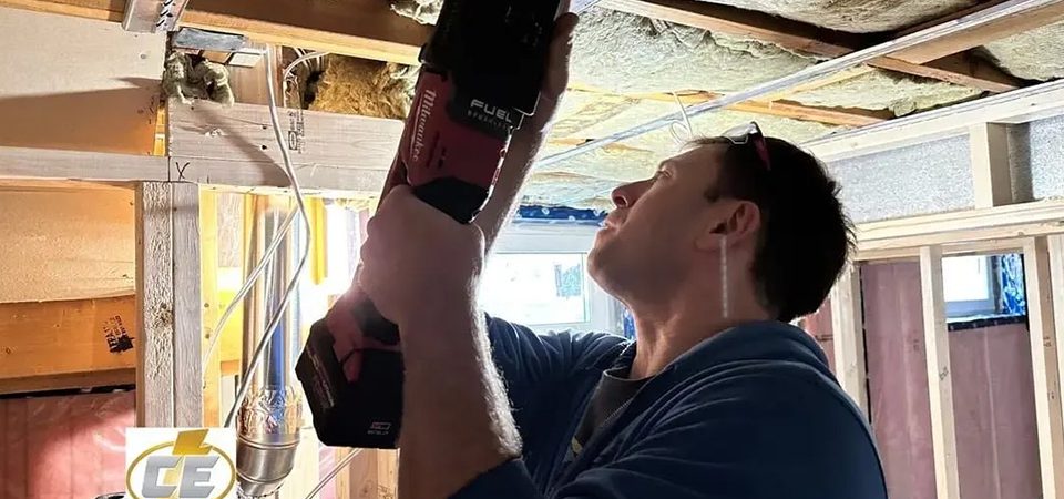 Man installing ceiling fixture with power drill.